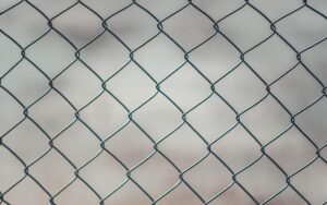 Detailed closeup of a metal chain-link fence with a blurred neutral background